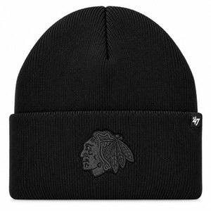 A black ribbed knit beanie hat featuring a tonal dark gray embroidered Chicago Blackhawks logo on the front cuff, with a small black '47 brand tag on the right side of the cuff.