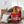 A red Chicago Blackhawks throw blanket draped over a gray armchair in a bright living room setting, with a white pillow on the floor and a wooden side table with a lamp in the background.