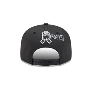 Black snapback cap shown from the back, featuring a white and black awareness ribbon with the NFL shield logo and the letters 'GSH' embroidered on the back.