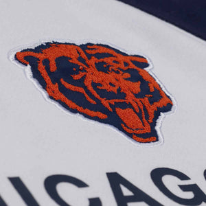 Close-up of a Chicago Bears embroidered logo patch on a white fabric background with navy lettering partially visible below.